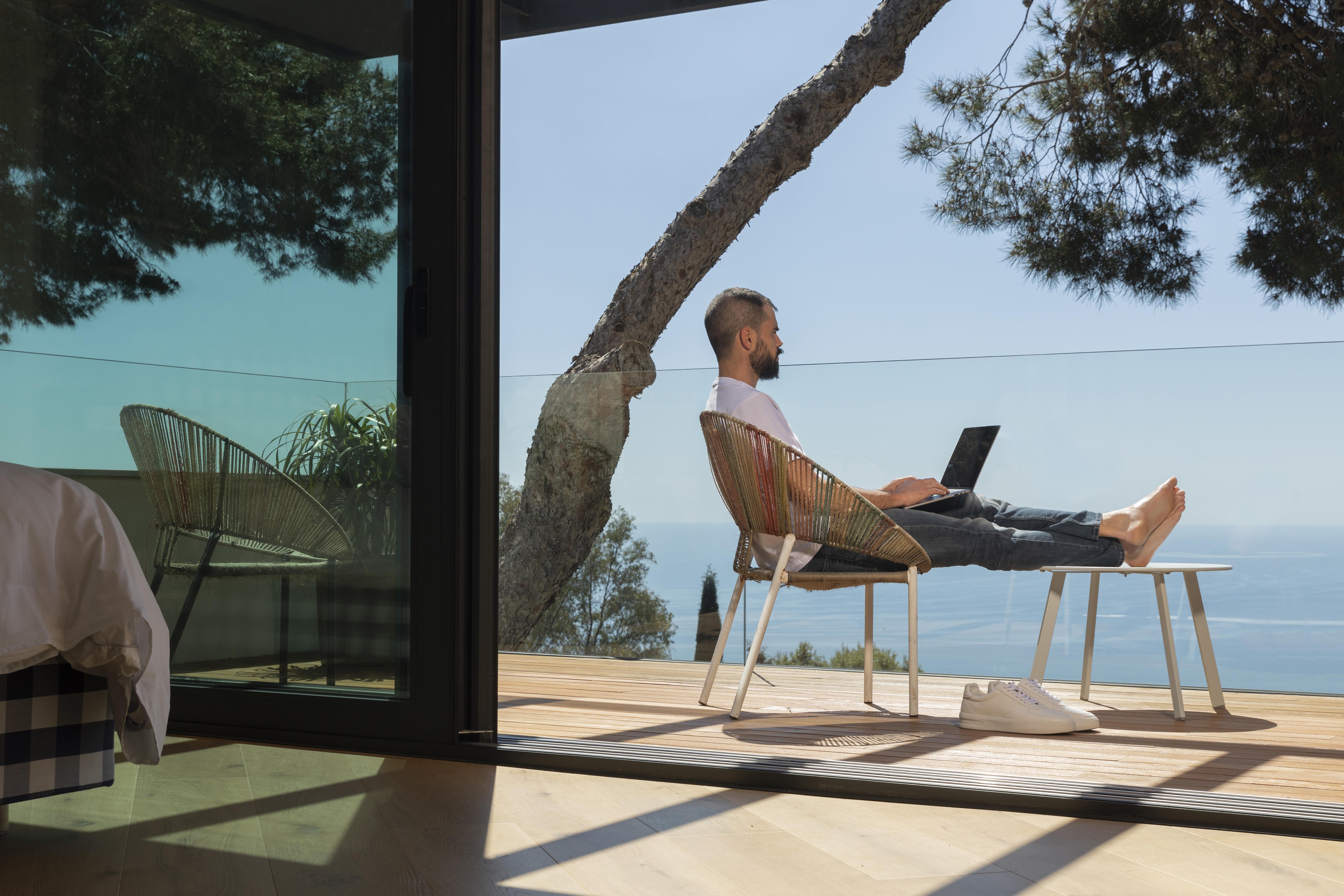 man working remotely on balcony with the the view 